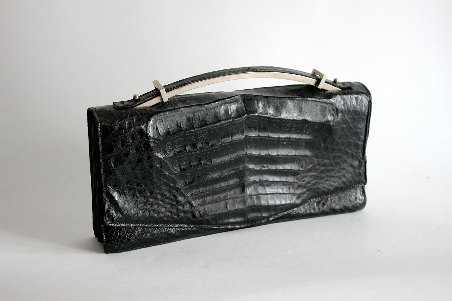 Persephone – early ’70s green-black crocodile-embossed leather clutch with silver-arc handle