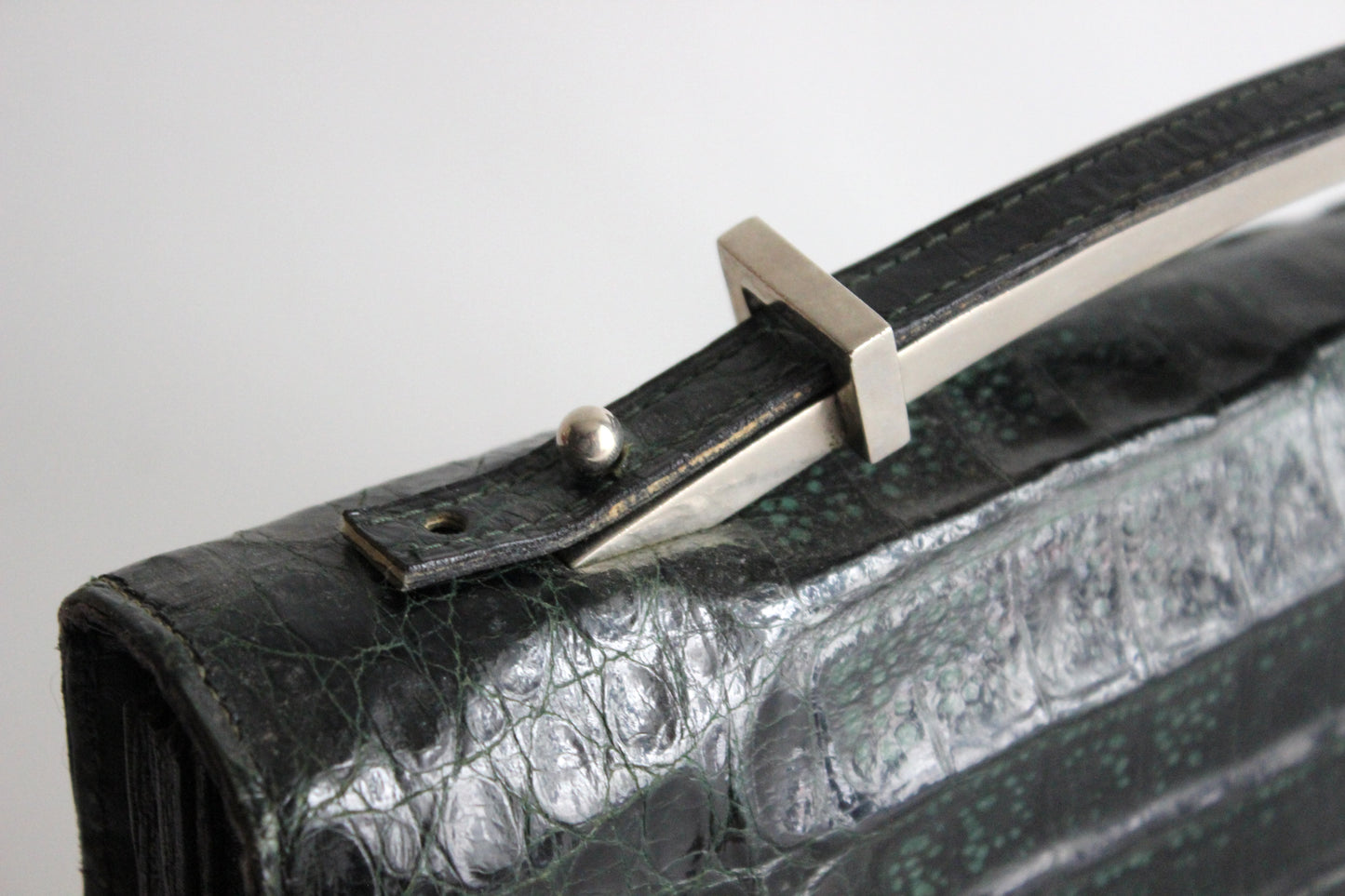 Persephone – early ’70s green-black crocodile-embossed leather clutch with silver-arc handle