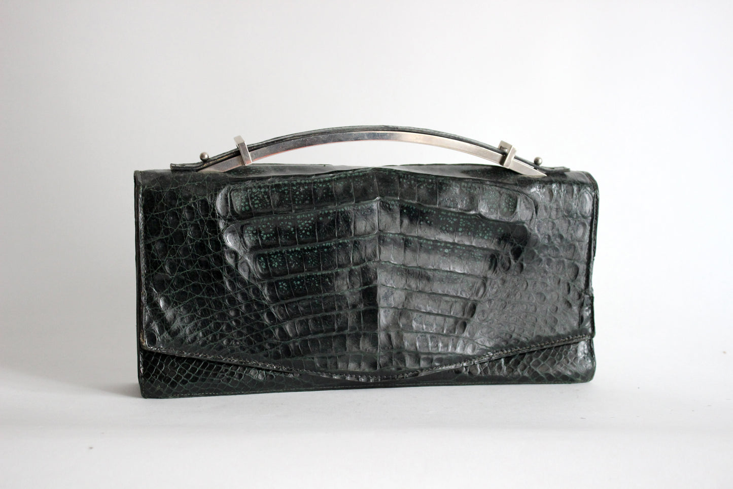 Persephone – early ’70s green-black crocodile-embossed leather clutch with silver-arc handle