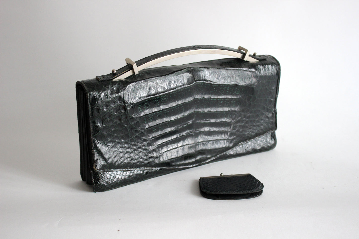 Persephone – early ’70s green-black crocodile-embossed leather clutch with silver-arc handle